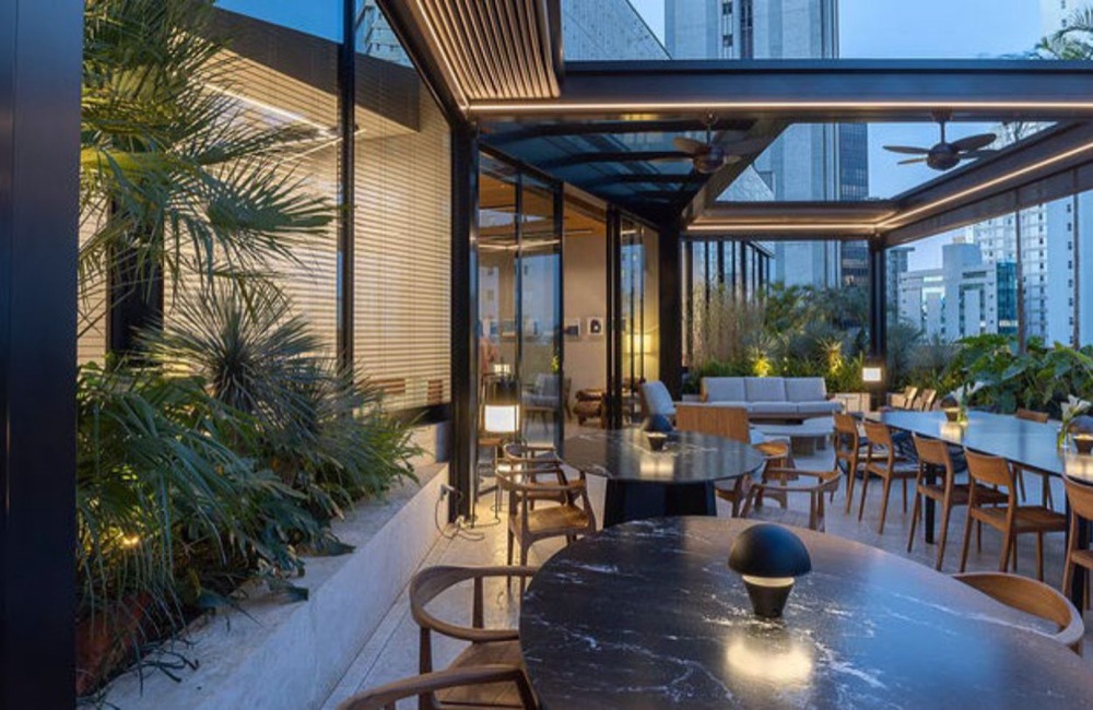 Terraço envidraçado com mesas e plantas