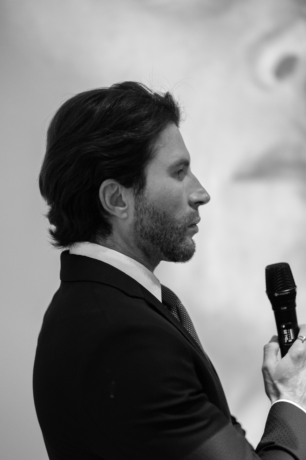 Dr. Danilo Morais de perfil, segurando um microfone, em preto e branco